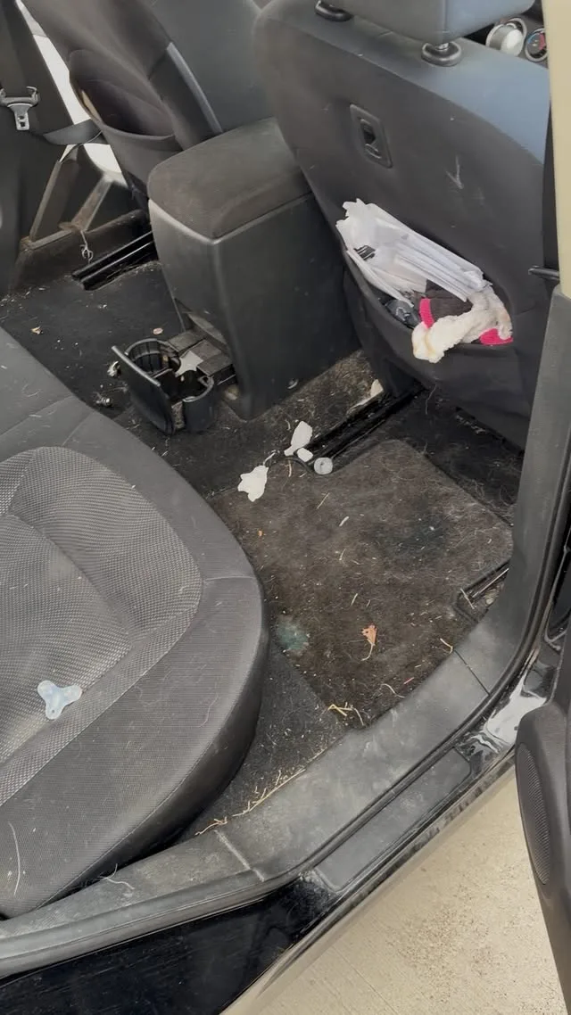 Rear passenger footwell before detailing — dirt, debris, and stained carpet